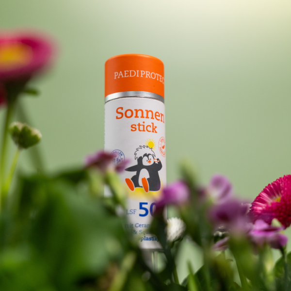Der PAEDIPROTECT Sonnenstick lugt hinter Blumen hervor