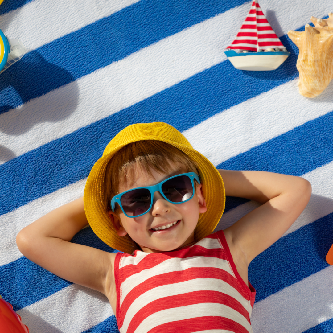 Junge entspannt sich auf Strandtuch mit Sonnenbrille und Sonnenhut Blog Bilder 52